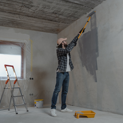 A handyman using a ladder to paint a room.